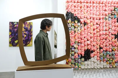 A man looks at an artwork, seen through a sculpture. 