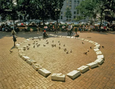 Archival image of an installation of concrete marks in the shape of a pond in a public plaza. Pigeons are in the center and people look on.
